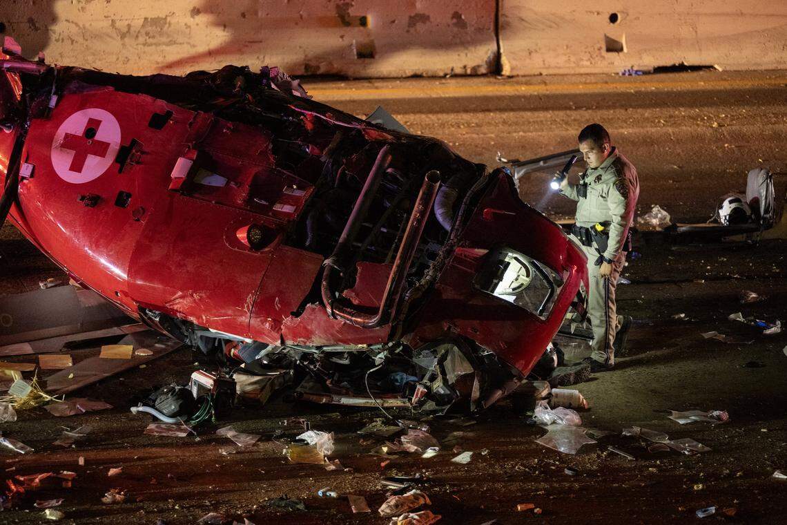 A CHP officer examines the crashed medevac helicopter on eastbound Highway 50 near 44th Street in Sacramento on Monday, Oct. 6, 2025, in Sacramento.