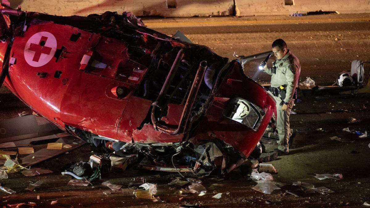 A CHP officer examines the crashed medevac helicopter on eastbound Highway 50 near 44th Street in Sacramento on Monday, Oct. 6, 2025, in Sacramento.