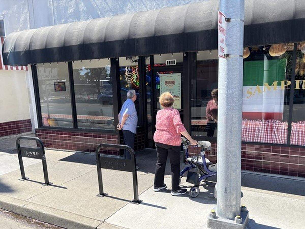 Margie Hahn and Mike Durant of Carmichael pause outside of offices for The Tower District at 1508 Broadway in Sacramento on June 1. A neon sign associated with Tower Records has been inside the offices since late 2025.