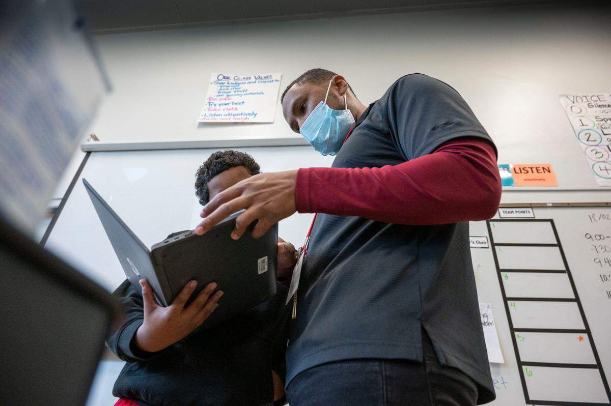 Jeremy Griggs, 29, a substitute teacher in the Sacramento City Unified School District, helps a sixth grade student with a writing assignment on Friday, Dec. 3, 2021, at Ethel Baker Elementary School. Teachers and substitutes are in short supply in Sacramento and around the country.