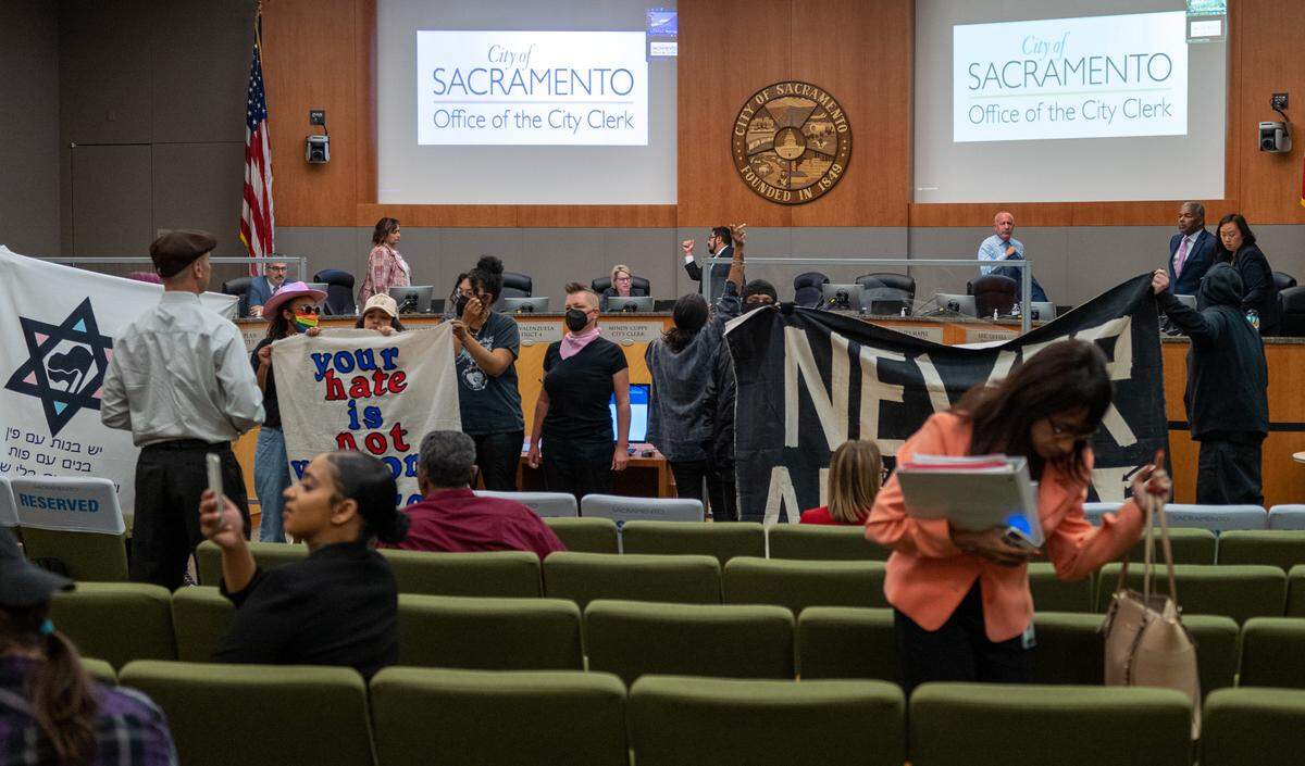 Sacramento Mayor Darrell Steinberg leaves the City Council chamber on Tuesday, May 23, 2023, after a group stormed the meeting demanding the removal Ryan Messano, in white shirt and hat, and a group he arrived with, forcing the City Council members to pause the meeting and move public comment to phone calls and Zoom.