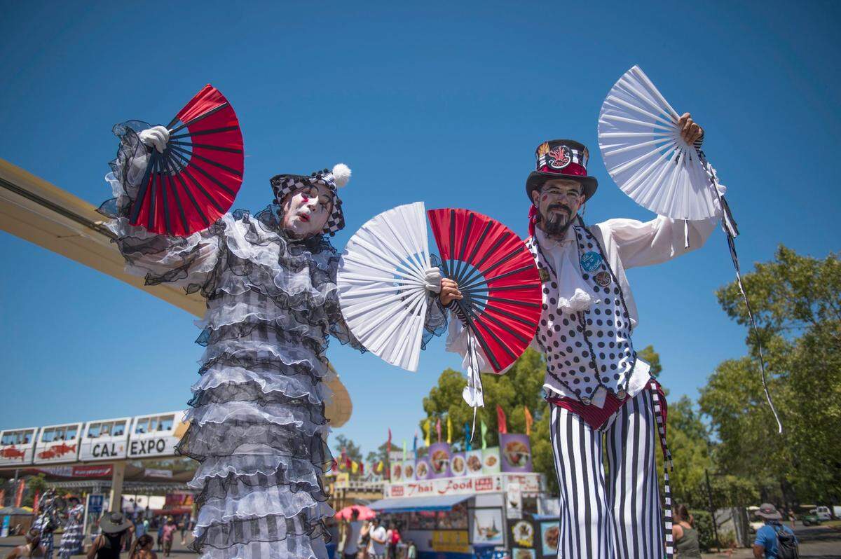 Circus performers on stilts Stephen Hues, left, and Richard Dalton fan visitors on a hot July day in 2016 at the State Fair.