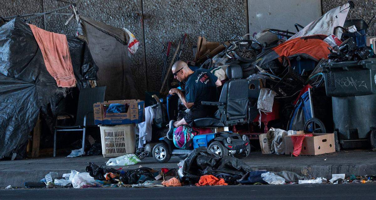 A person in a motorized wheelchair maneuvers his way past a sidewalk campsite on Broadway in Sacramento on Oct. 5 after a Sacramento Community Response team visited with the homeless residents. The outreach team informed the campers about a new city ordinance that requires four feet of clearance so that wheelchair users won’t be obstructed on the sidewalk.
