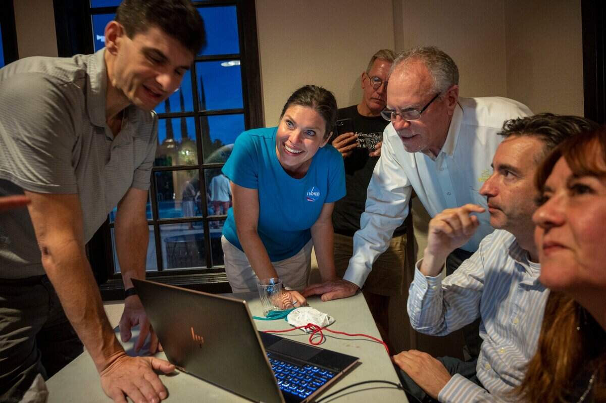 Sacramento City Council candidate Lisa Kaplan, center, stands with campaign supporters as they look at early results during her election watch party in North Natomas on Tuessday, June 7, 2022.