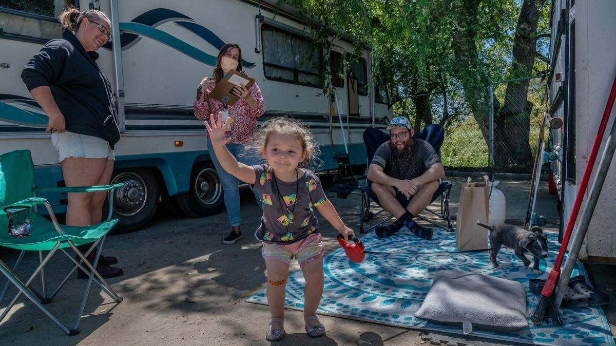 Cillían Coyle, 2, is happy to greet people as she holds on to a leash for her new puppy Maverick while her parents April Crowell, 27, left, and David Coyle, 27, right, get registered at the previous Safe Ground encampment near Miller Park in April 2021.