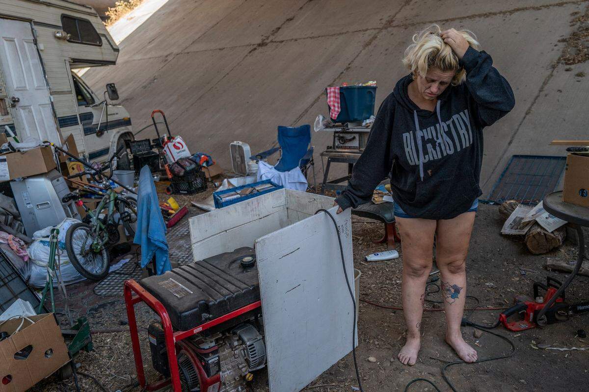 Laurene Ivey stands next to a generator on Aug. 25 in the homeless encampment under a freeway in north Sacramento where she lives near her mother Gwen Mayse. She lived at the homeless encampment near Howe Avenue and Fair Oaks Boulevard with her mother before it was cleared, but they left before the eviction to save their belongings.