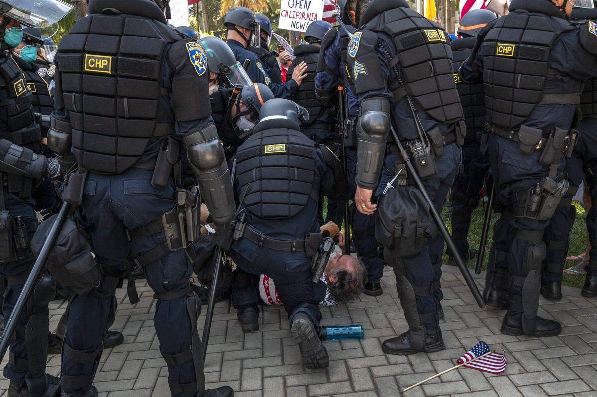 A protester is attended to after he was pushed and fell as police moved forward to clear the Capitol in Sacramento on Friday, May 1, 2020, while he was demonstrating against Gov. Gavin Newsoms stay-at-home order to slow the spread of the coronavirus.