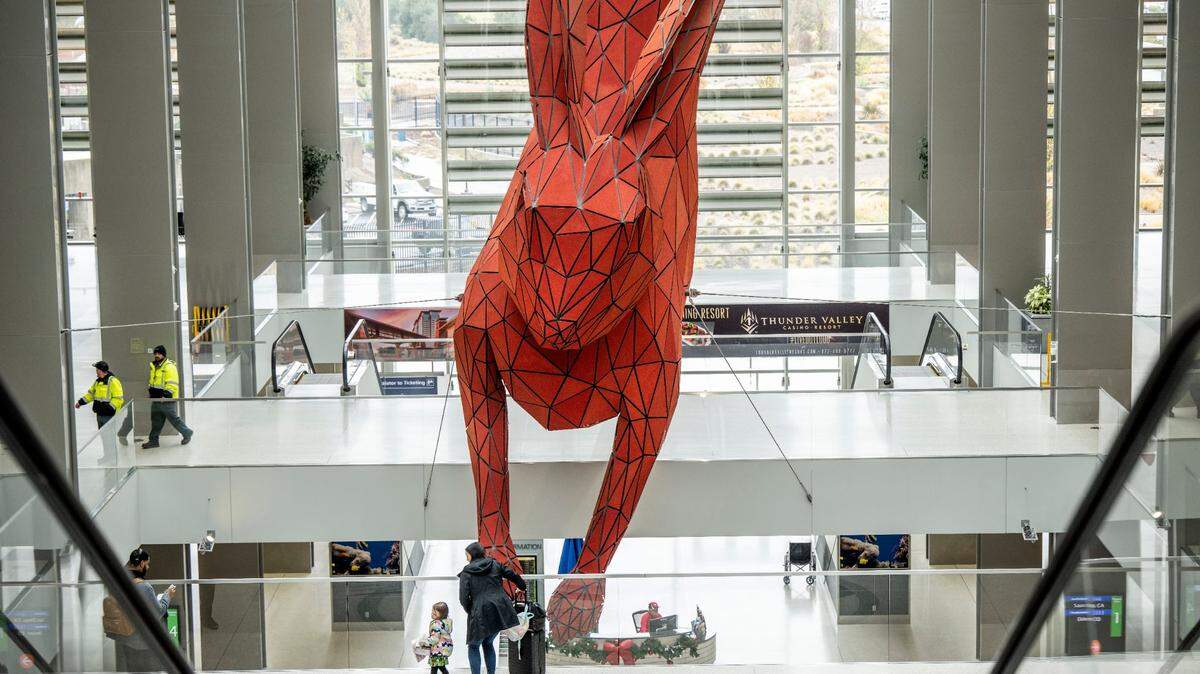 Amy Azzi of Seattle and her daughter look at “Leap” the 56-foot-long red rabbit created by Denver artist Lawrence Argent at the Sacramento International Airport’s Terminal B on Thursday, Dec. 29, 2022.