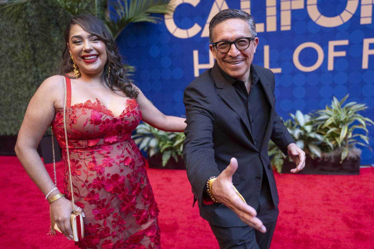 Pablo Espinoza, deputy director of communications for the California Department of Housing and Community Development, right, reaches out to shake hands as he walks the red carpet before an induction ceremony of the 19th class of California Hall of Fame inductees at the California Museum in Sacramento on Thursday, March 19, 2026.