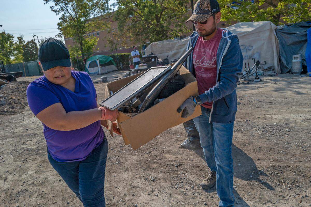 Leticia Huerta, 50, and her son Raul Huerta, 20, pick up trash at a homeless encampment across the street from Garden Valley Elementary School in South Natomas on Friday. They have been coming to clean up the area every Friday with a group of parents who have children that attend the school.