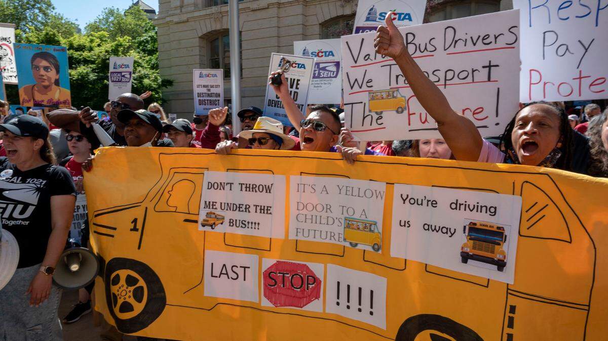 Angelia Spagner right, a bus driver with Sacramento City Unified School District’s transportation department, holds a school bus sign with other bus drivers as they rally in front of City Hall on Friday, Day 3 of the strike. Both the Sacramento City Teachers Association and the classified staff, represented by SEIU Local 1021, are striking.