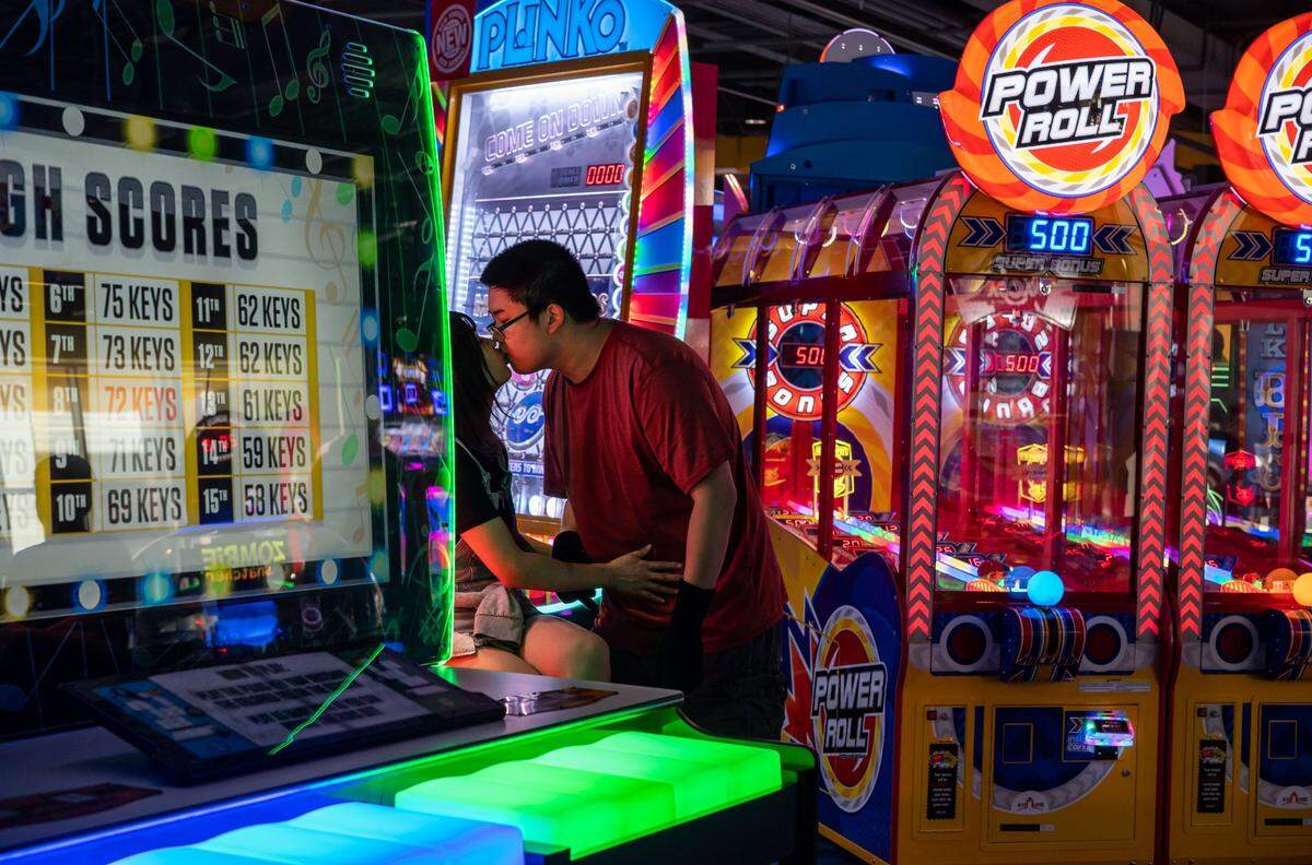 Rayven Zhang, of Sacramento, leans in to kiss his wife, Keara Zhang, after playing Wacca, an arcade rhythm game from Japan, on opening day at Round1 Bowling & Amusement at Westfield Galleria at Roseville on Saturday.