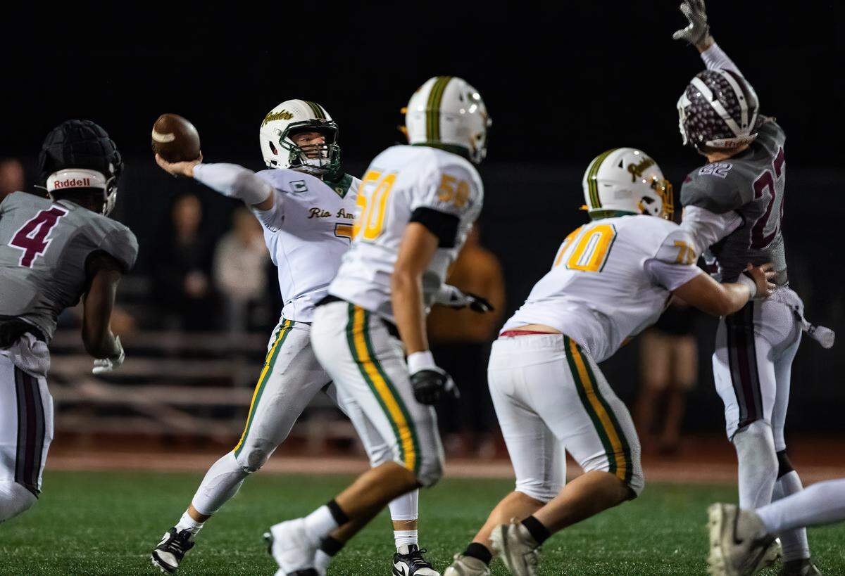 Rio Americano Raiders quarterback Ryder Trantham (7) throws downfield as Woodcreek Timberwolves outside linebacker Jeremiah Whyte (4) and defensive back Kingston Acosta (27) apply pressure in a CIF Sac-Joaquin Division III semifinal playoff game in Roseville on Friday, Nov. 21, 2025. 