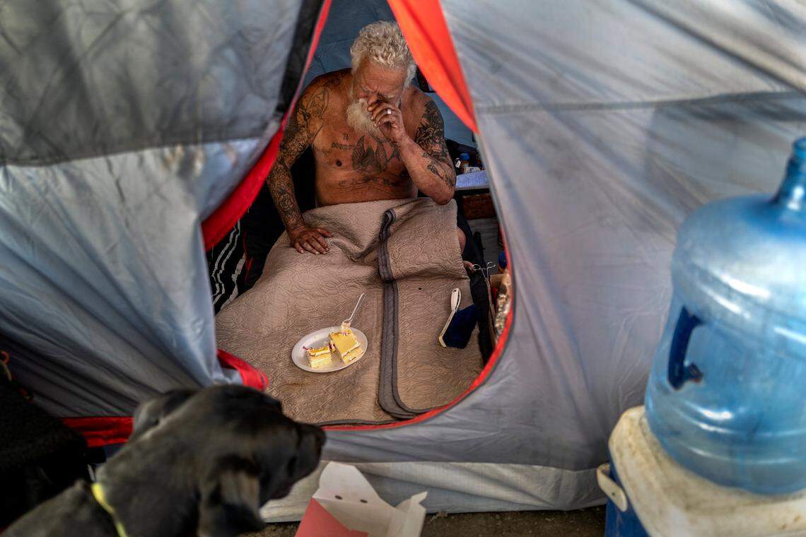Mark Yates, who turned 70 on Monday, stresses over being removed from “Camp Resolution,” as he is about to eat a piece of birthday cake alongside his dog Brutus at the self governing homeless encampment at Arden Way and Colfax street in North Sacramento on Tuesday.