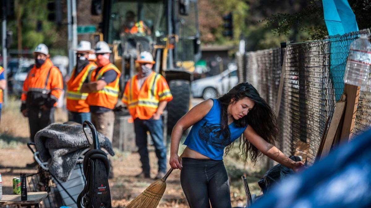 As Caltrans workers wait to clear the site, Emily Bolshakoff, 31, moves items on Tuesday, Oct., 5, 2021, from a camp she shares with boyfriend Mark Tvrdik near 29th and G streets in midtown Sacramento.