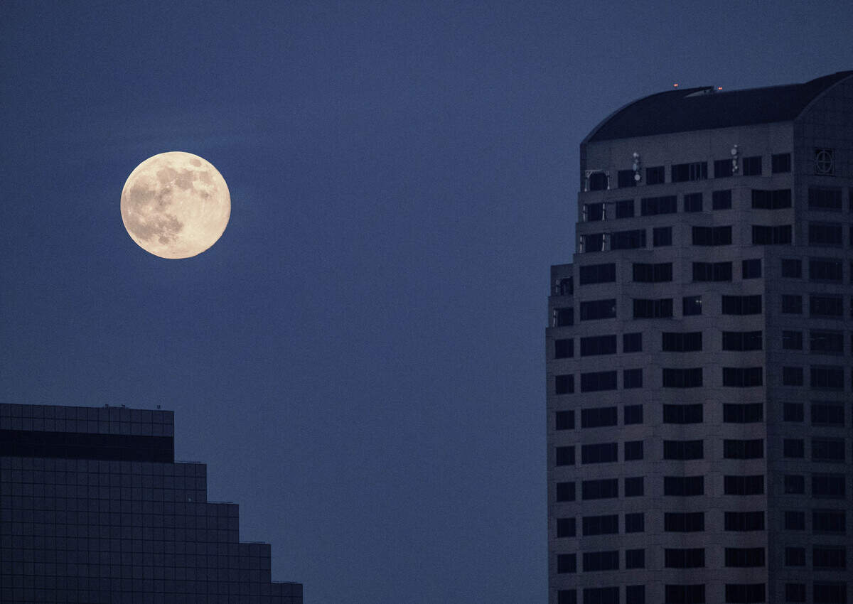A supermoon climbs over the Emerald Tower in downtown Sacramento at dusk on Thursday. It’s the last full moon of the year.