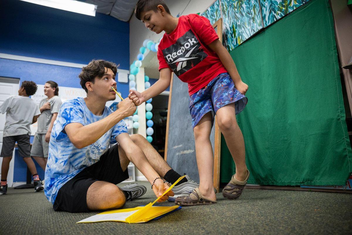 José Salazar, left, one of graduates of The GreenHouse who now works there, congratulates a youth for having a good day Monday. If Salazar hadn’t discovered the neighborhood youth program when his family moved there in 2015, “I think I would honestly be a whole different person,” he said.