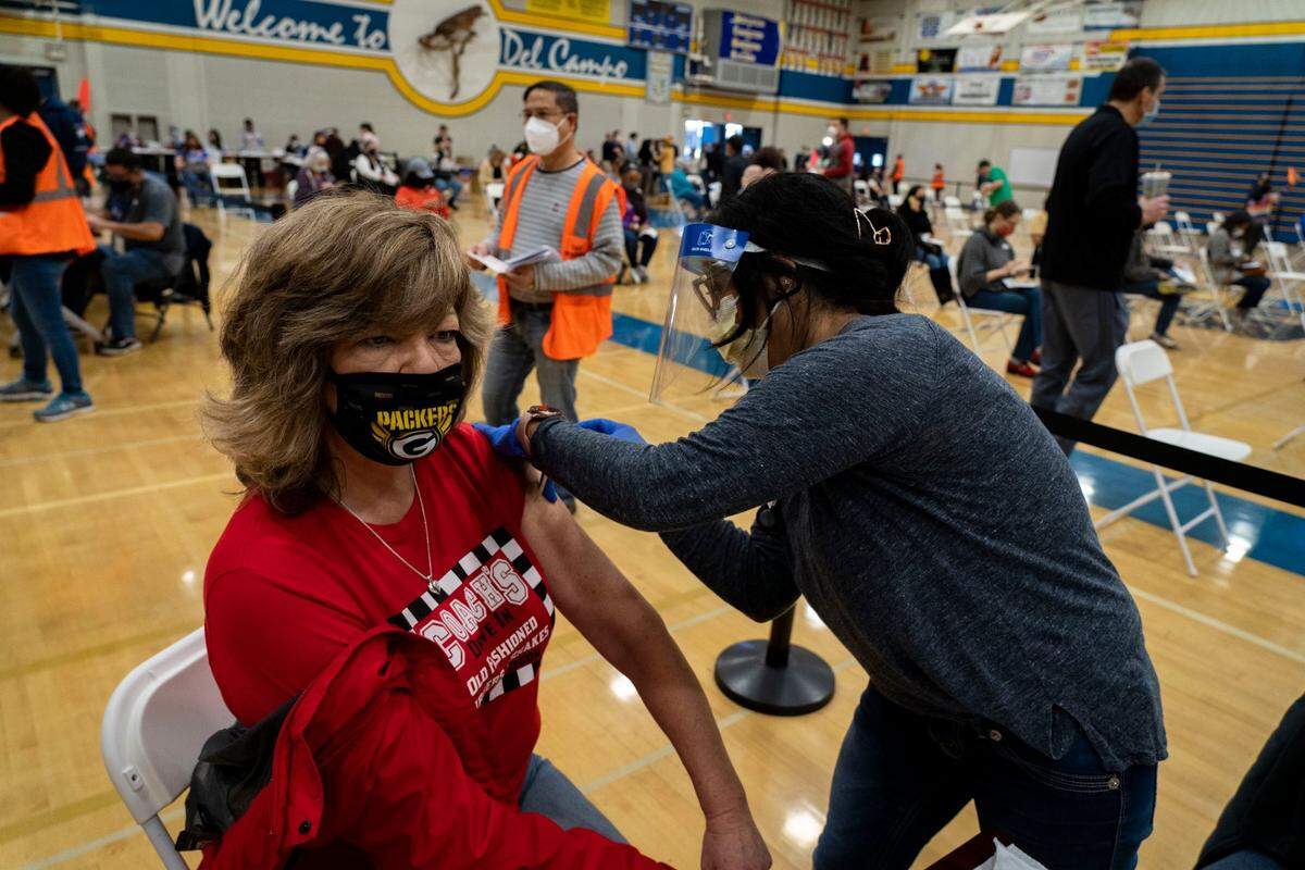 Sylvan Middle School secretary Kathleen Mathias receives the COVID-19 vaccine from Dignity Health registered nurse Cristina Gonzales on Saturday, Feb. 20, 2021, at Del Campo High School in Fair Oaks. The clinic was held by the San Juan Unified School District in partnership with Dignity Health, and was expected to vaccinate about 2,000 district employees and community members over age 65.