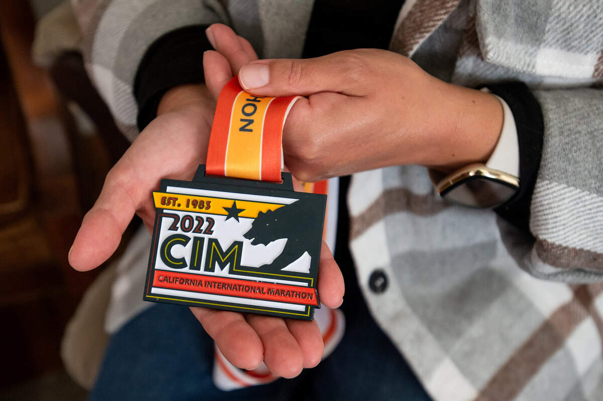 Augustina Kuen, wife of Aaron Kuen, shows Aaron’s 2022 California International Marathon medal on Sunday, Jan. 22, 2023, at her home in Elk Grove. Scott Abbott, the CIM race’s director, gave her the medal and she is waiting to give it to Aaron when he becomes conscious.