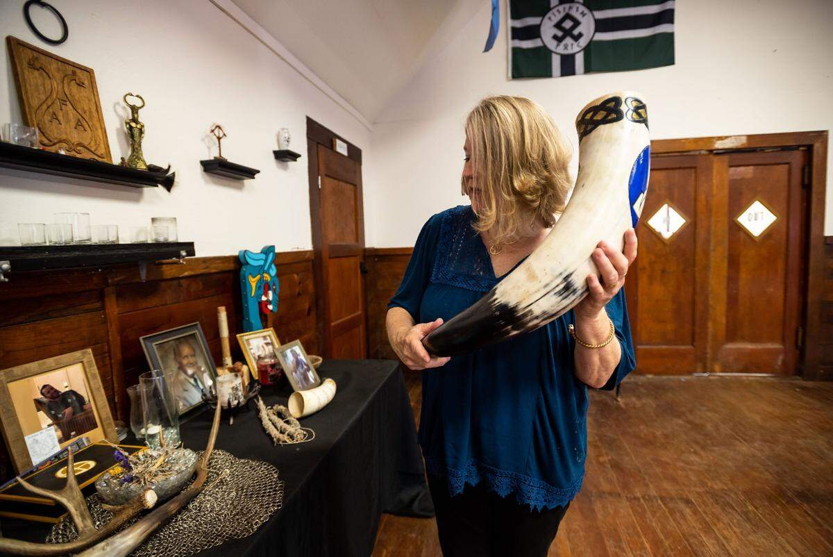 Sheila McNallen holds the Asatru Folk Assembly’s main ritual horn while showing the inside the “Odinshof” on July 27, 2021, in Brownsville, Yuba County. McNallen’s husband, Stephen McNallen, founded the pagan whites-only religious organization.