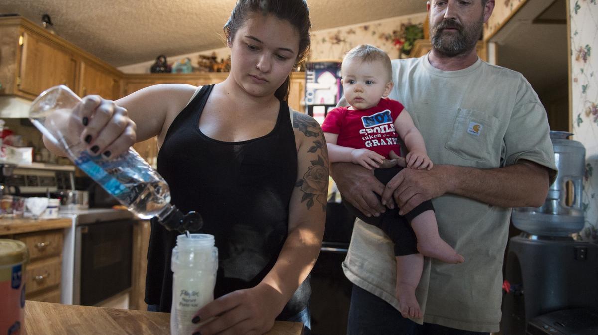 Taylor Hoff, 20, pours bottled water while mixing up baby formula for her little brother, Hunter, who is held by their dad, Michael Hoff, Sunday, May 27. The family uses bottled water to drink, cook and brush their teeth. The Hoff family and other residents at the Rancho Marina Mobile Home & RV Park in Isleton complain about the quality of their drinking water.