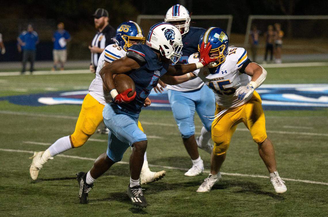 The Destiny Christian Lions’ Malakai Taione (5) stiff arms the Linden Lions’ Braden Busalacchi (15) on the way to a long gain on Friday.