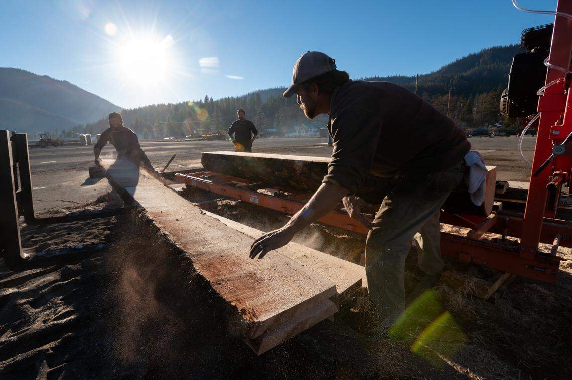 Dan Kearns, right, and Seth Coffland move lumber cut from a ponderosa pine that burned in the Dixie Fire at a new mill in Crescent Mills on Friday, Dec. 3, 2021. Both men work for J&C Enterprises, a logging company that’s partnering with the Sierra Institute.