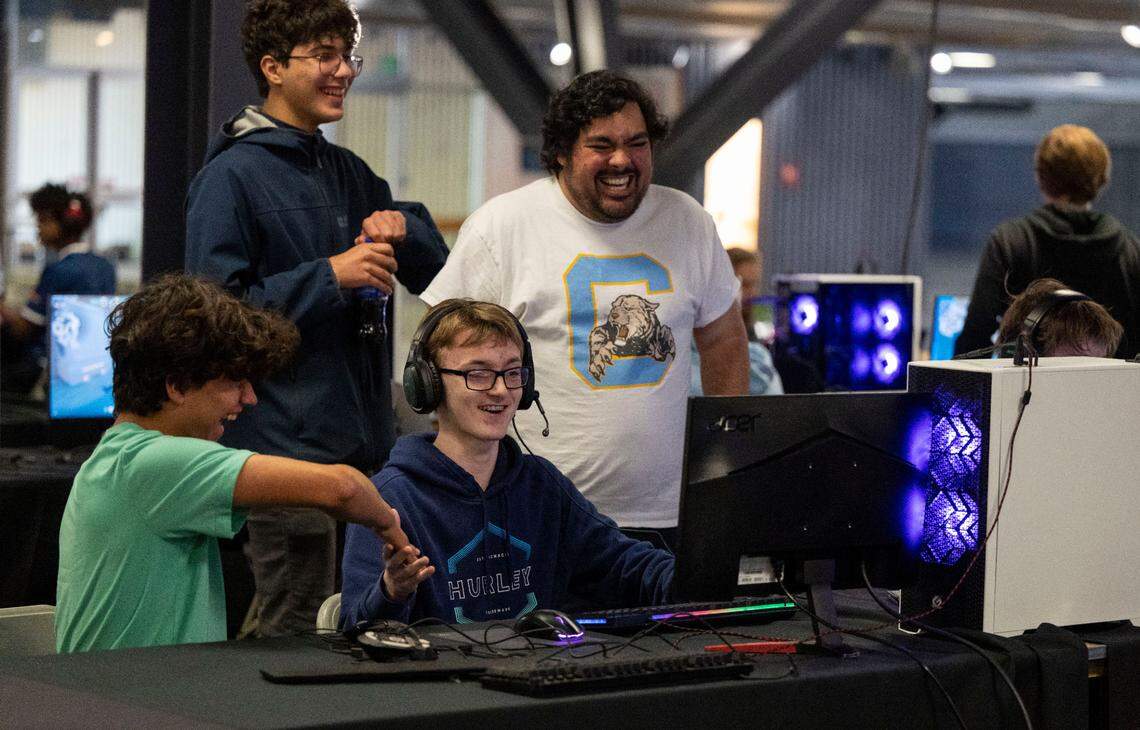 Center High School player Landin Cook, middle, gets a handshake by team supporter Angel Ferrell, left, and his coach, Eric Cabral, right, while competing Sunday as Sacramento hosts its first major electronic gaming tournament at Cal Expo.