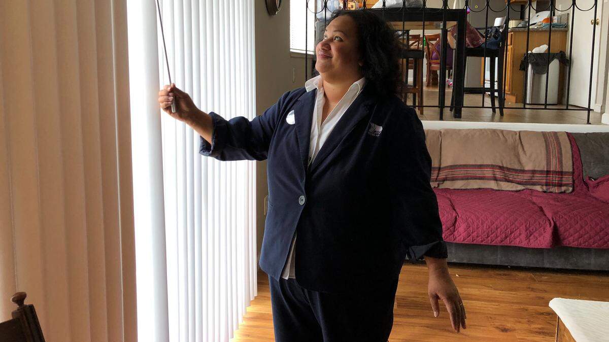 Puna Folau Makihele opens the window blinds at her Room and Board in South Sacramento.
