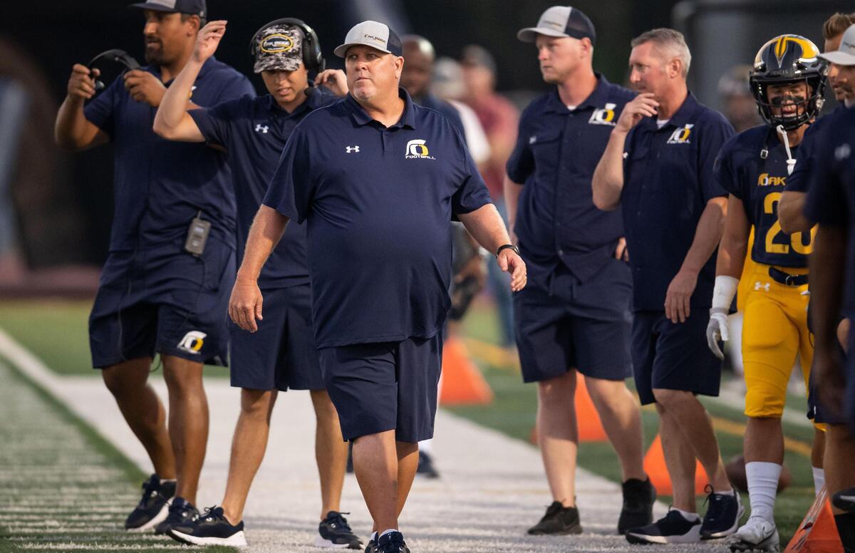 Oak Ridge Trojan head coach Casey Taylor, left of center, watches surrounded by his assistants and support as his players take on Vacaville in the first quarter of the high school varsity football game Friday at Oak Ridge High School in El Dorado Hills.