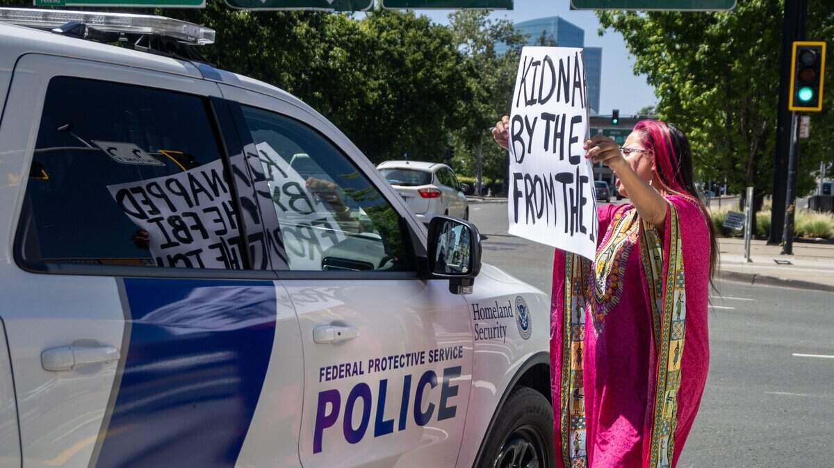 A protester puts up her poster in front of a Homeland Security vehicle outside of the Matsui Federal Courthouse where the hearing for Carlos Mendoza was held in Sacramento on Tuesday, April 14, 2026.