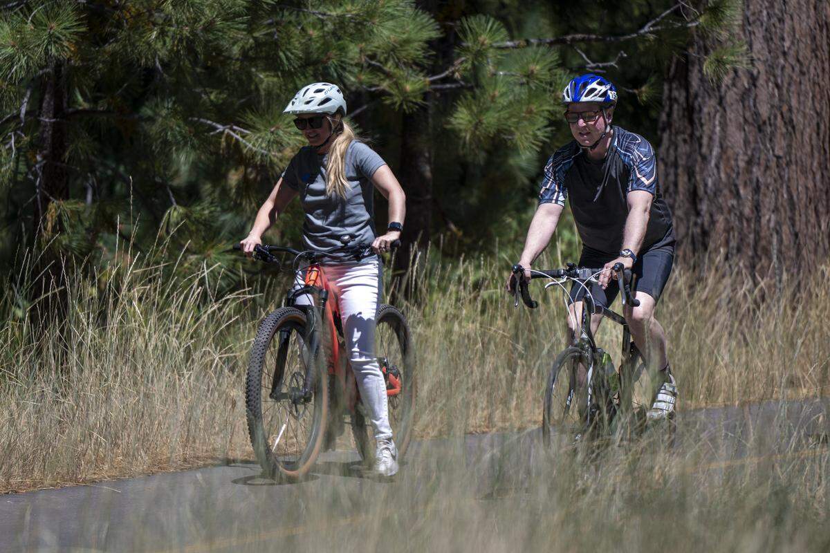 Sen. Adam Schiff, right, rides a bike on the newly dedicated Dianne Feinstein West Shore Tahoe Trail in Tahoe City on Thursday.
