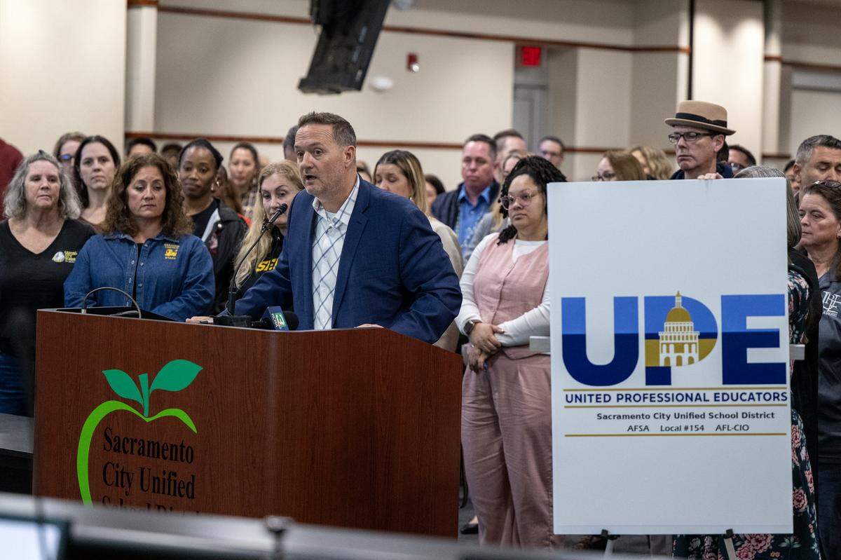 Garrett Kirkland, principal of Hiram Johnson High School and president of the United Professional Educators union, is flanked by supporters as he speaks to the Sacramento City Unified School District school board on Thursday at the Serna Center in Sacramento.