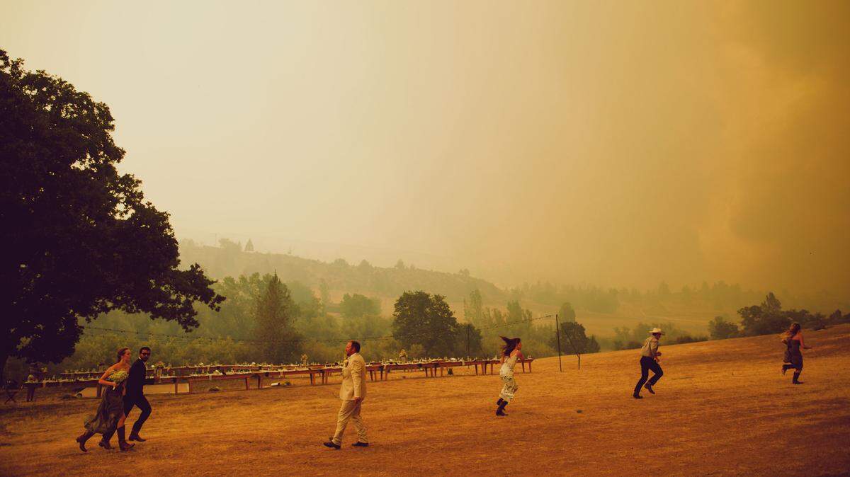 People at the wedding of Ellie and Taylor Denney run as an evacuation order is issued for the Klamathon Fire in the community of Hornbrook on Saturday, July 7, 2018.