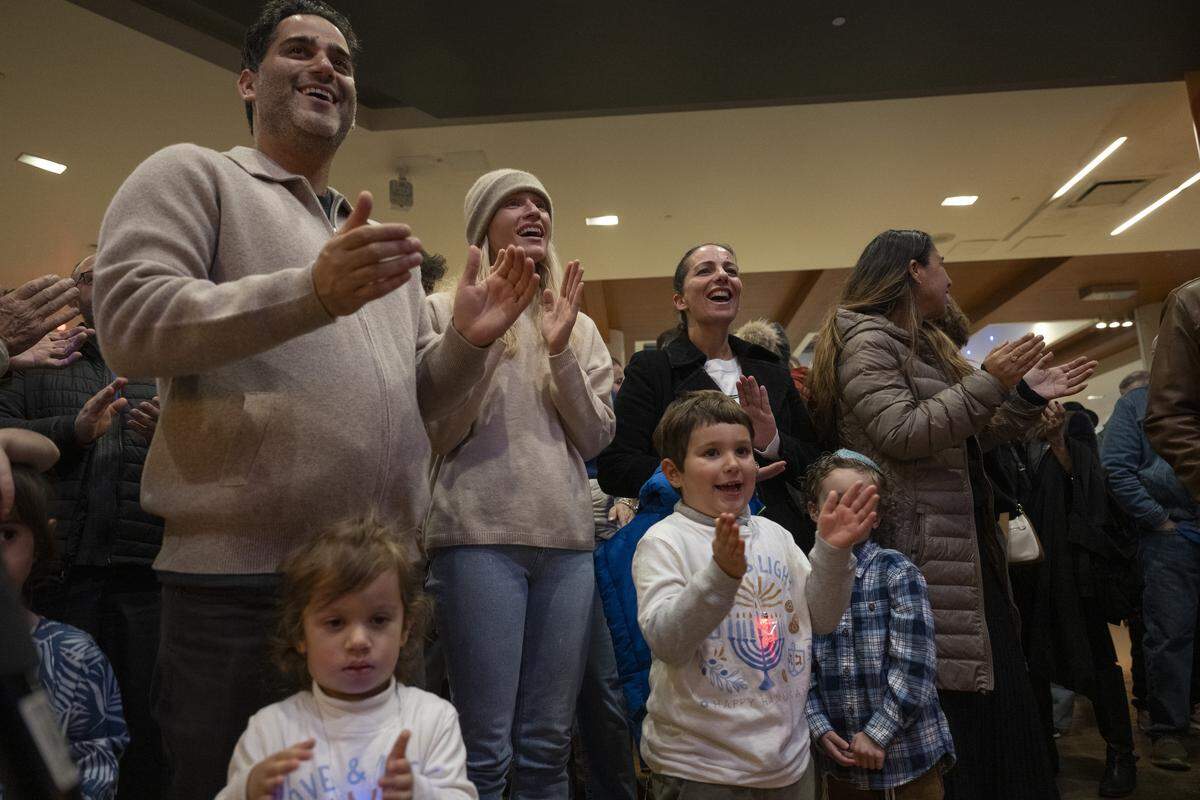 Members of the Roseville and Placer County Jewish community sing together during a menorah lighting on the first night of Hanukkah at the Westfield Galleria in Roseville on Sunday.