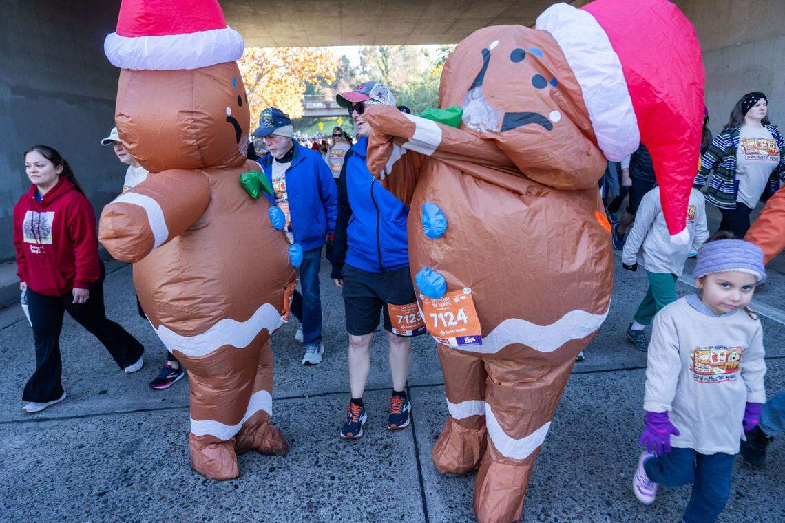 Linda Kingsbury takes a break with as her husband Mark attempts to adjust his gingerbread suit as they participate in the Run to Feed the Hungry on Thursday in East Sacramento.