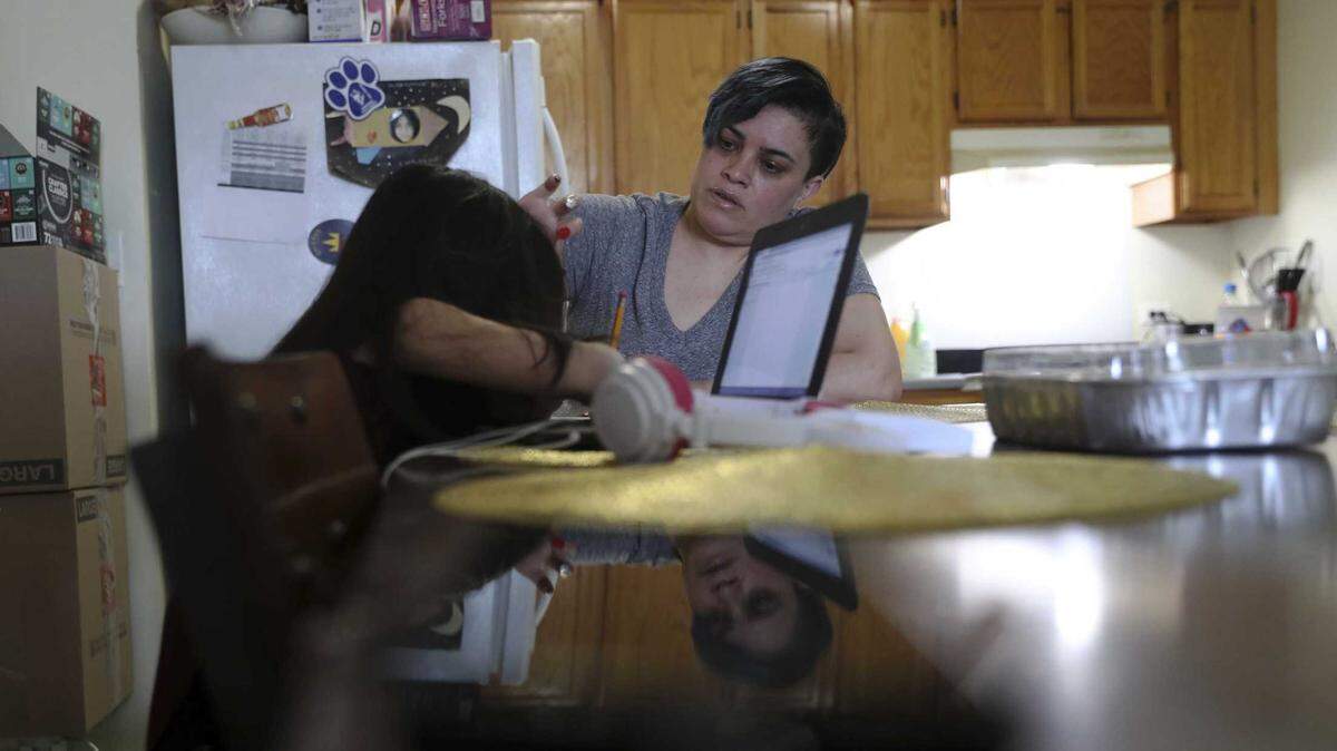 Chicago parent Rosa Esquivel, right, helps her 10-year-old daughter, Veronica Esquivel, after virtual school.