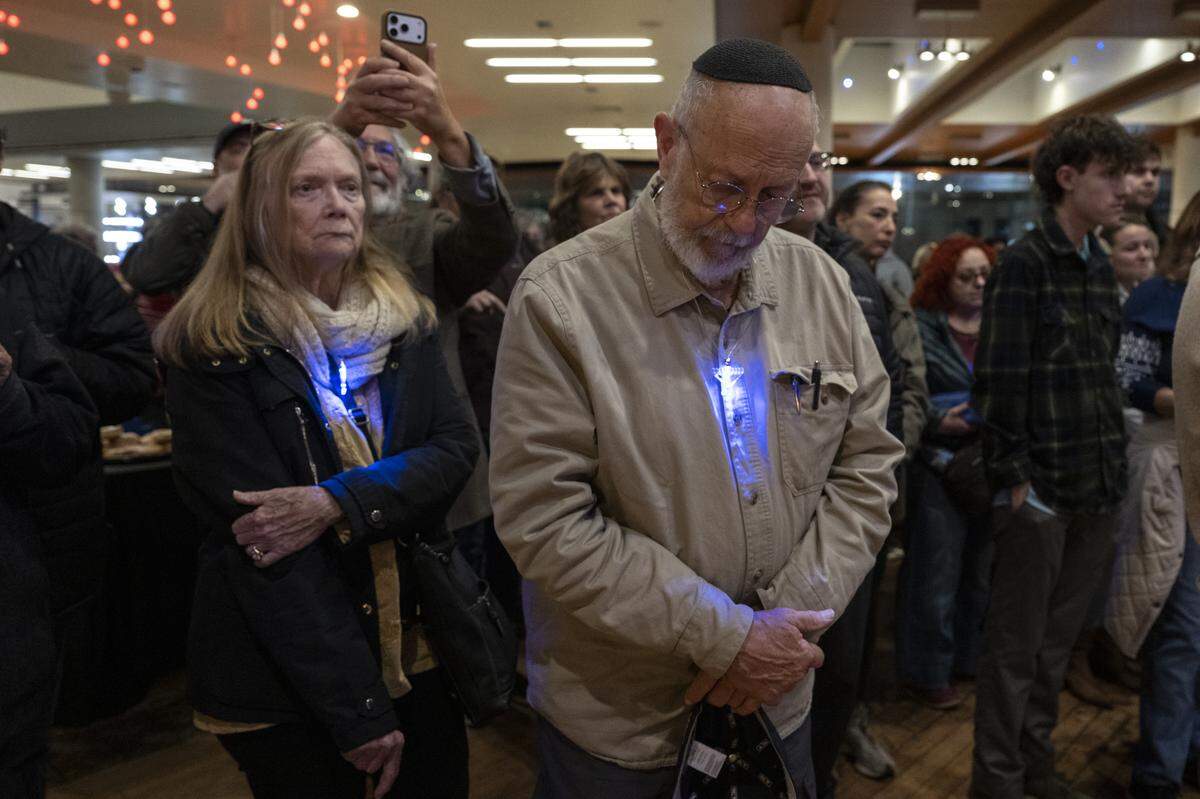 Members of the Roseville and Placer County Jewish community pray together during a menorah lighting on the first night of Hanukkah at the Westfield Galleria in Roseville on Sunday.
