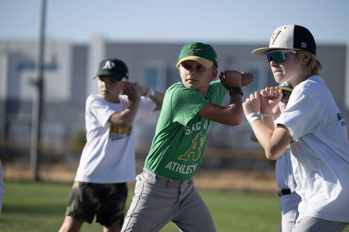 Cyde Copeman, center, of Davis, practices his batting stance with other players during Brent Rooker’s youth sports camp in Sacramento on Thursday.