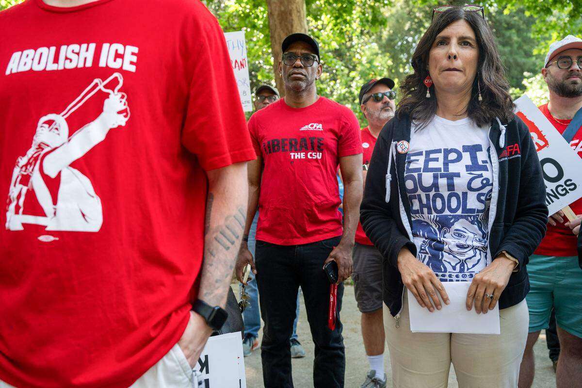 Margarita Berta-Avila, president of the California Faculty Association labor union, right, holds a copy of a speech she gave at Southside Park in Sacramento while listening to other speakers at the “A Day Without Immigrants” 20th anniversary march on Friday.