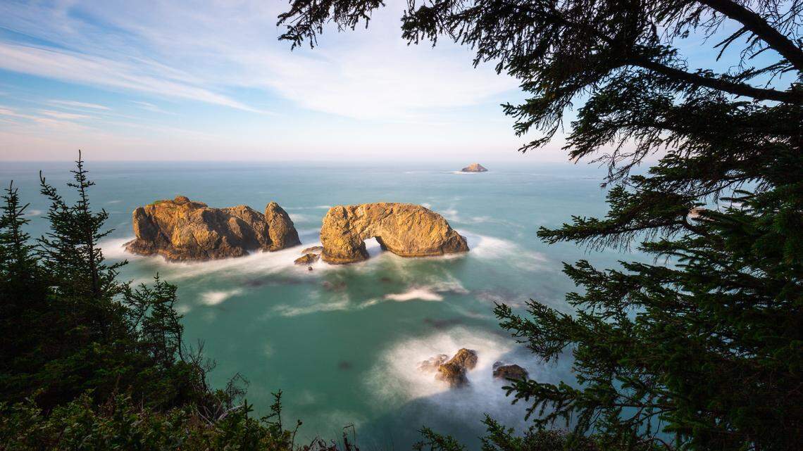 Arch Rock on the Oregon coast in daytime. Photographer Jay Shah captured a shot of bioluminescent tides around the rocks at night.