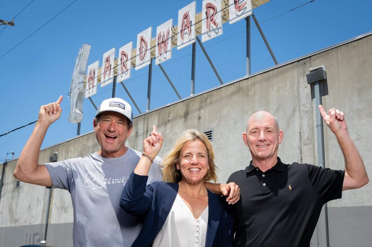 From left, Michael Heller, Allison Otto and Ted Messner stand beneath the old Hollywood Hardware sign at its new location on the roof of Otto Construction near 3rd and R streets in Sacramento earlier this month.