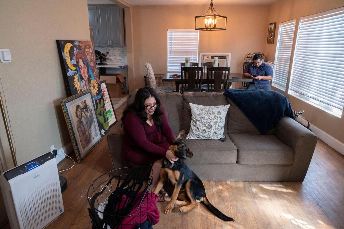 Albanita Erebia plays with dog Lulu as her fiancé Daniel Savala checks in on work on his cell phone on Friday, Oct. 1, 2021, in the Sacramento home they purchases earlier this year.