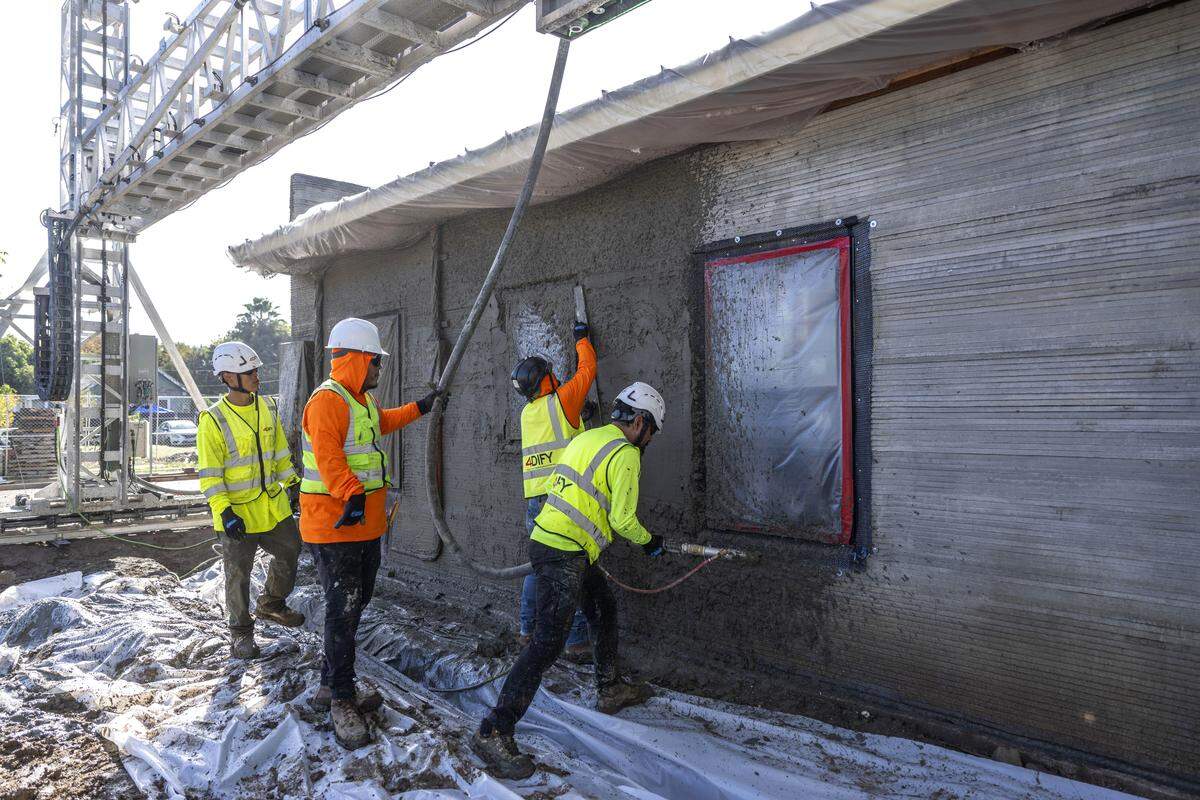 Workers spray concrete on the first 3D printed home in Yuba County on Thursday.