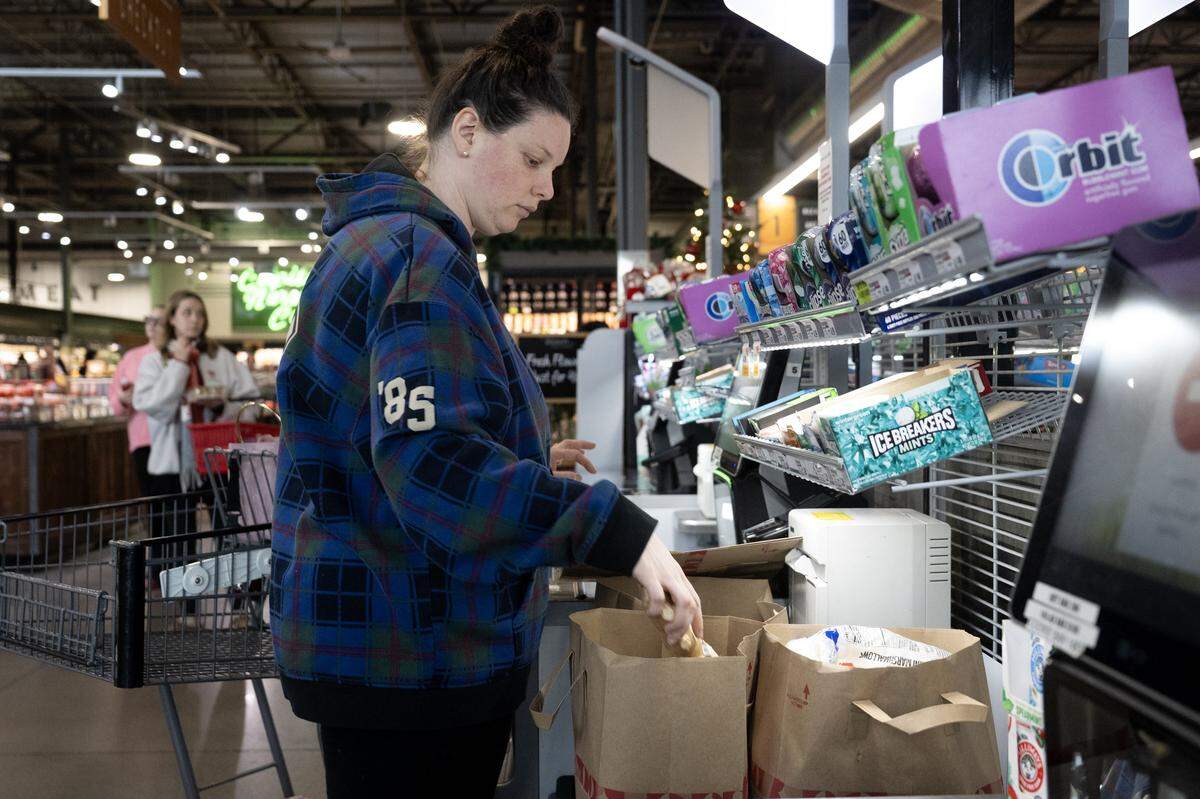 Customer Nina Culliver, 32, uses paper bags to load her grocery purchases at Raley’s in Sacramento on Dec. 19. A new California law banning all plastic carryout bags at many types of stores takes effect Jan. 1.
