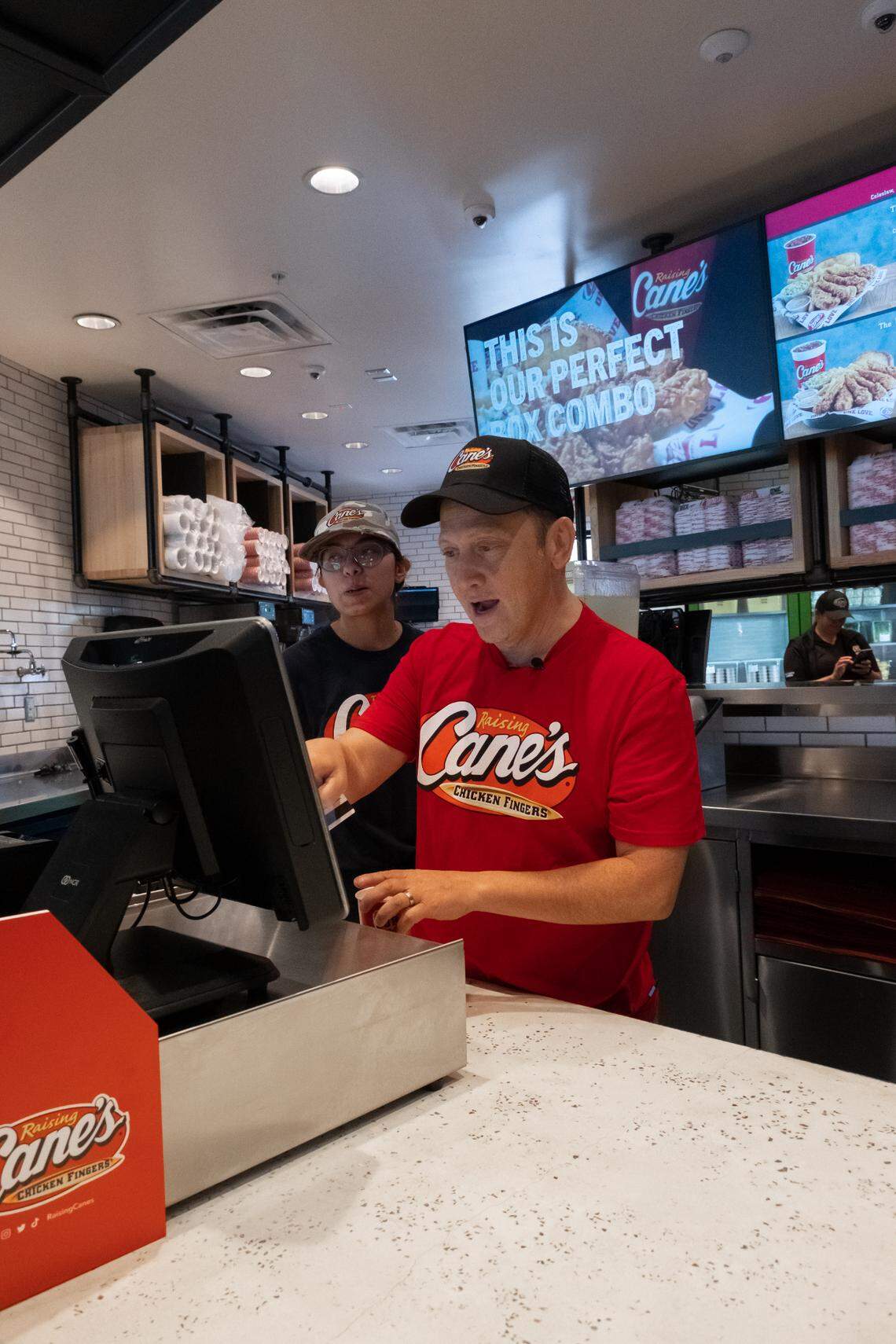 Rob Schneider works the register at Raising Cane’s in Phoenix, Arizona.
