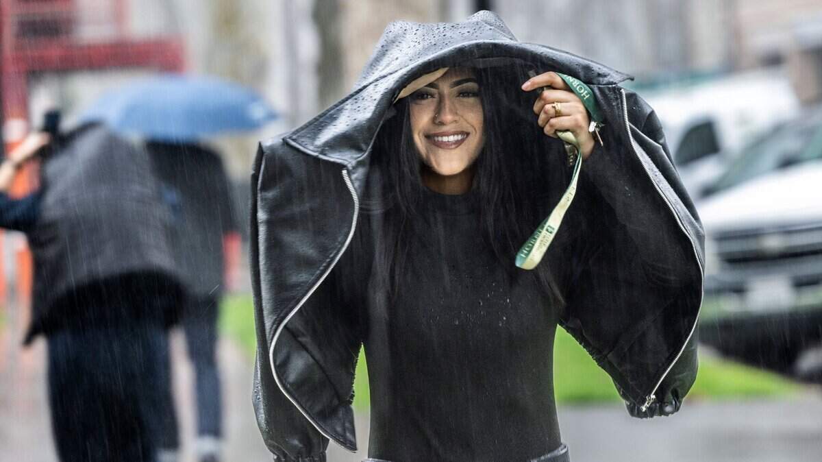 Azaria Loya, of Sacramento, covers herself from the rain on Friday, March 1, 2024, on 22nd Street in midtown Sacramento.