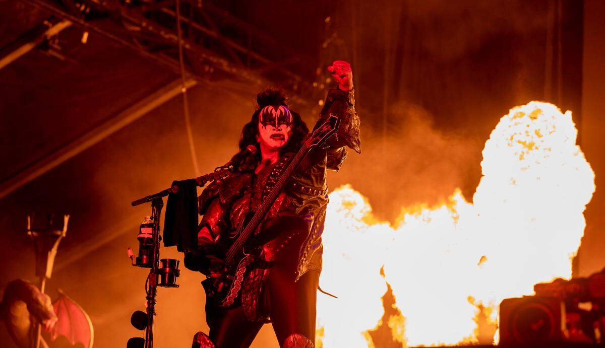 Gene Simmons raises his fist as fire goes off behind him as Kiss headlines on Friday night at the Aftershock Festival .