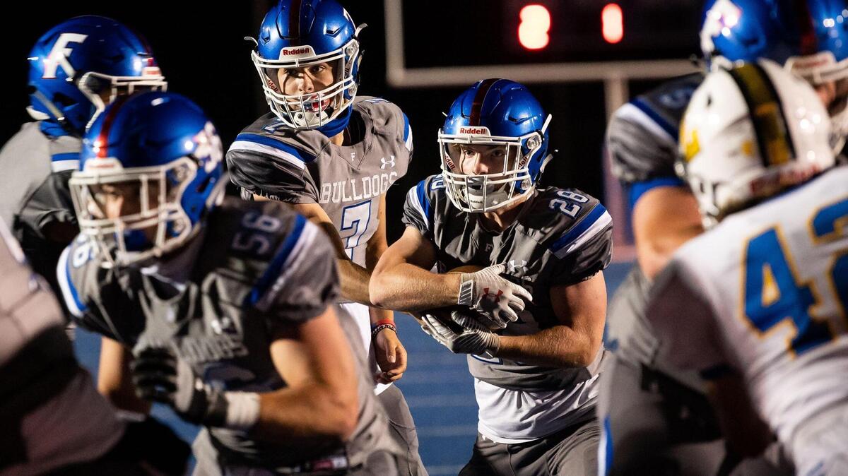 Folsom quarterback Tyler Tremain hands the ball off to Mitch Anderson in the fourth quarter to run in the team’s fifth touchdown against Lincoln during the high school football game Friday, April 9, 2021, at Folsom High School in Folsom. Folsom beat Lincoln 41-14.