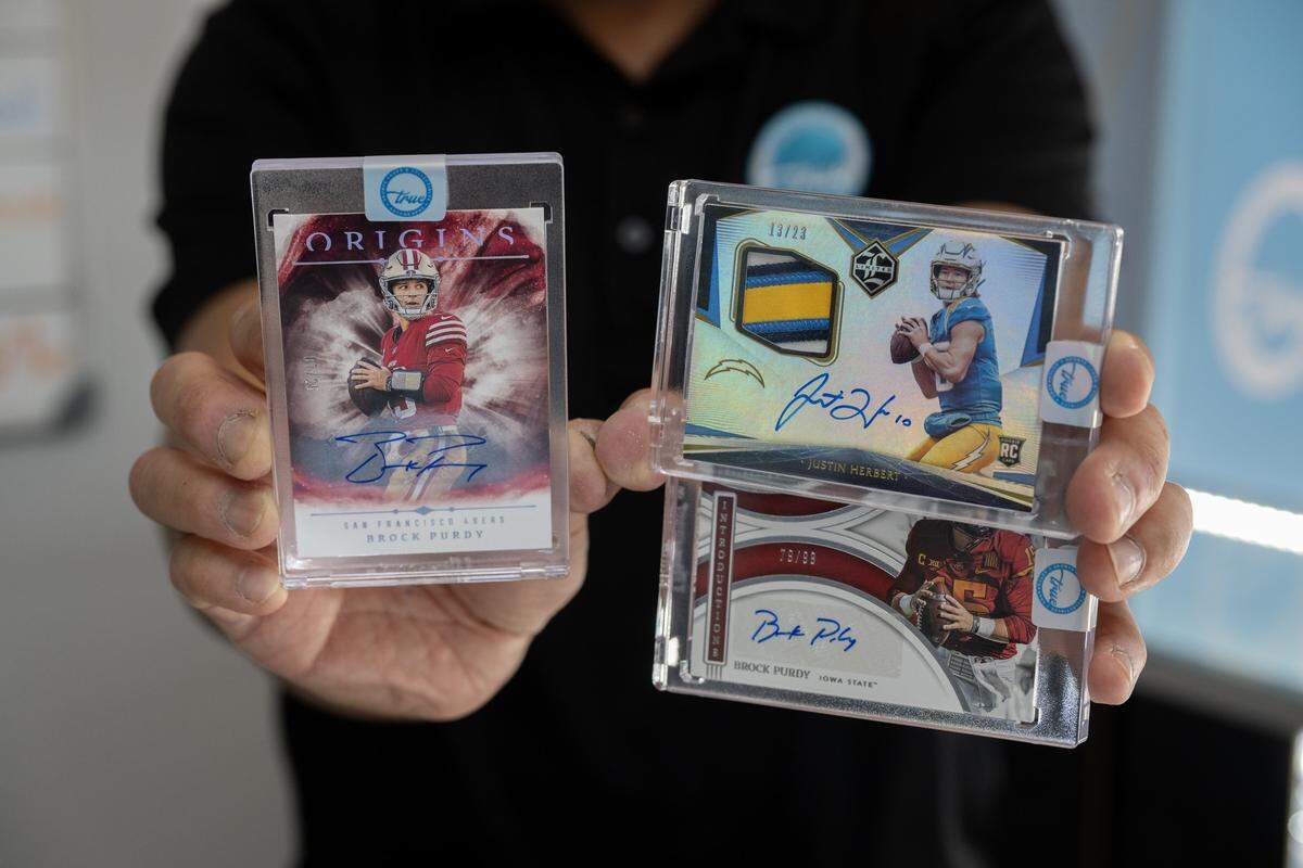 Imran Poladi holds collectable sports cards featuring NFL quarterbacks Brock Purdy and Justin Herbert at his store, True Sports Cards, in Rocklin earlier this month.